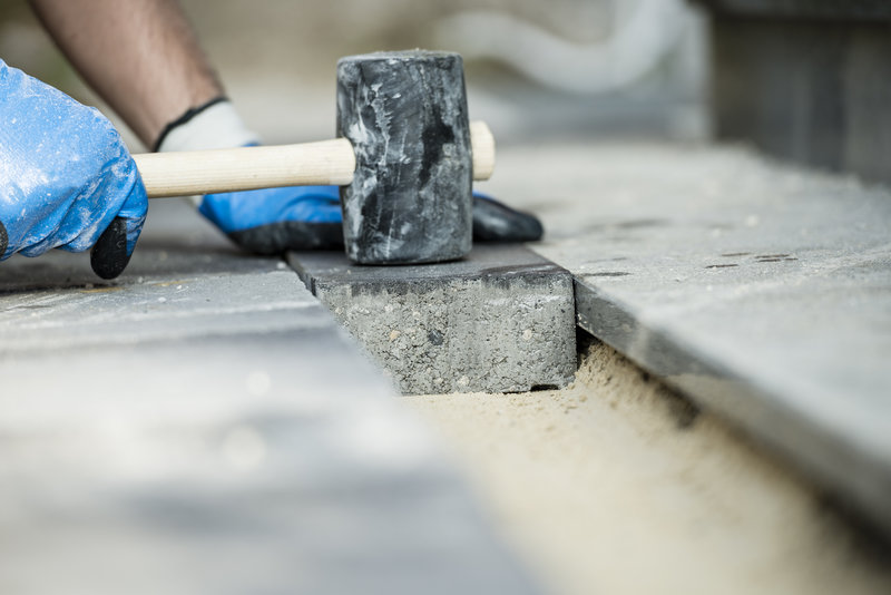 Builder laying a paving stone or brick